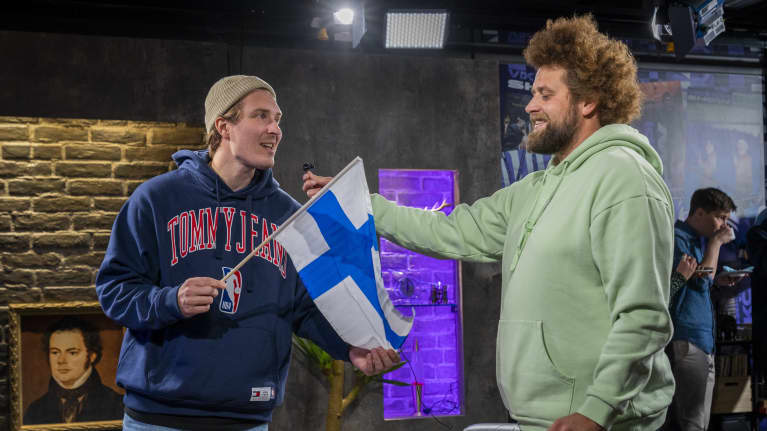 Toimittajat Juuso "Köpi" Kallio ja Ville "Viki" Eerikkilä studiossa Suomen lipun kanssa.