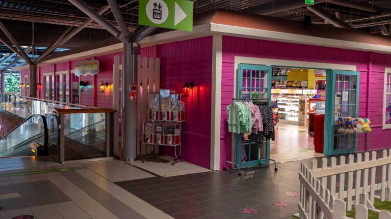 Kauppakeskuksen yläkerrassa on pinkki talon mallinen myymälä, jonka avoimista ovista näkyy leluja.