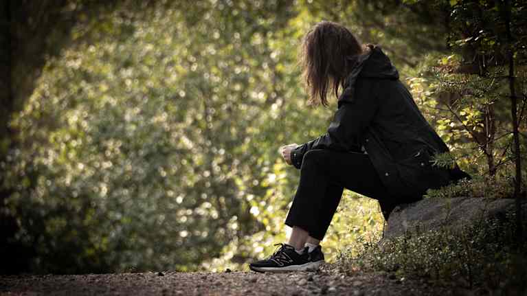 A woman sits on a stone.