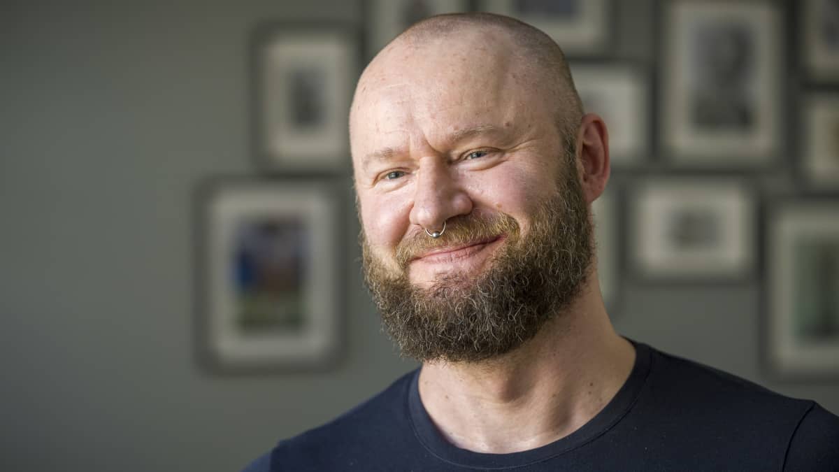 Henrik Heiskanen katsoo kaameraan taustalla potretteja.