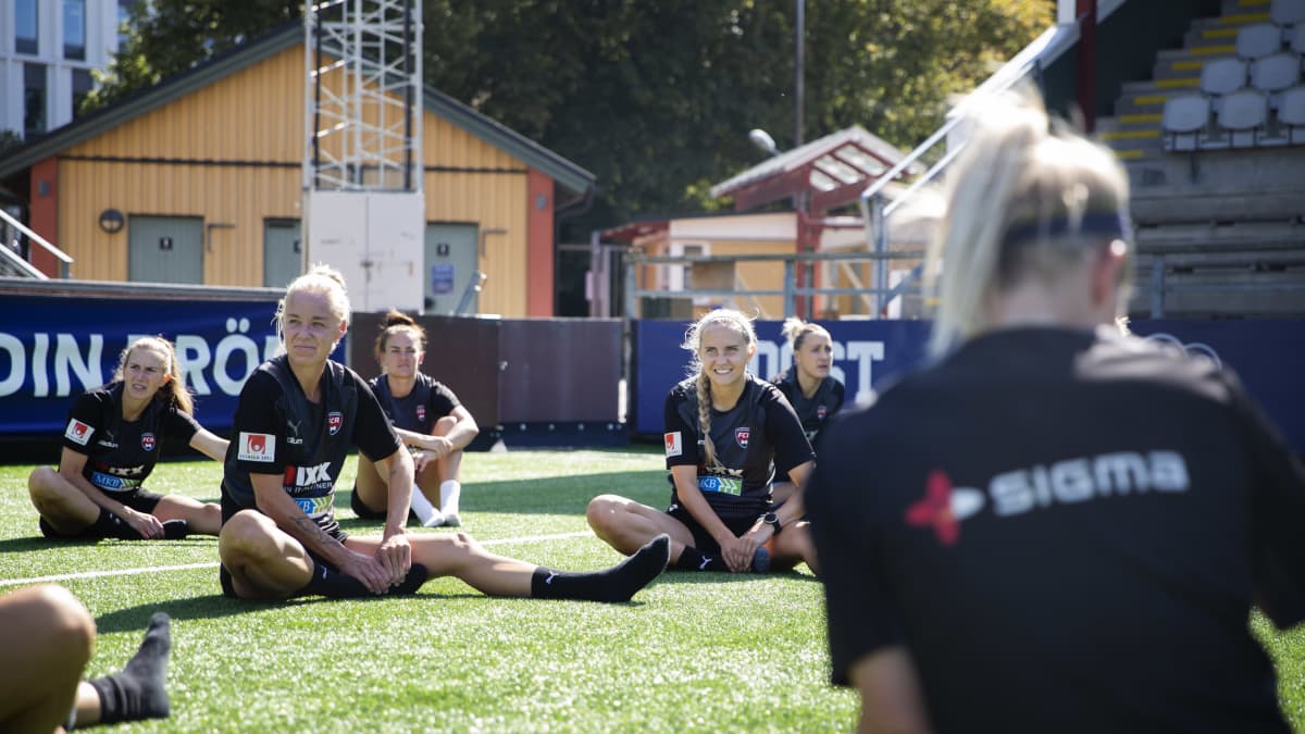 naisjalkapalloilijat venyttelevät nurmella