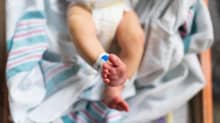 A newborn infant wearing a diaper in a crib.