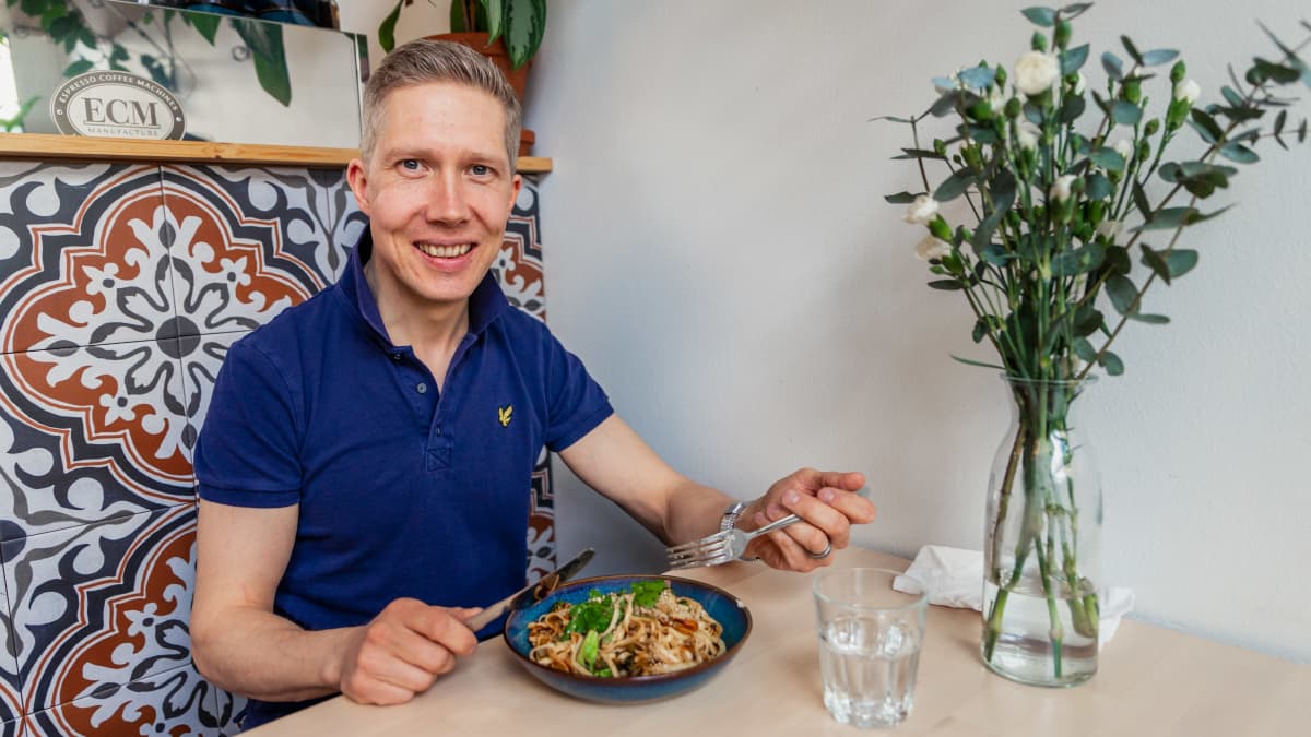 Klaus Raunela istuu pöydässä ja edessään hänellä on kasvisruokaa lautasella.