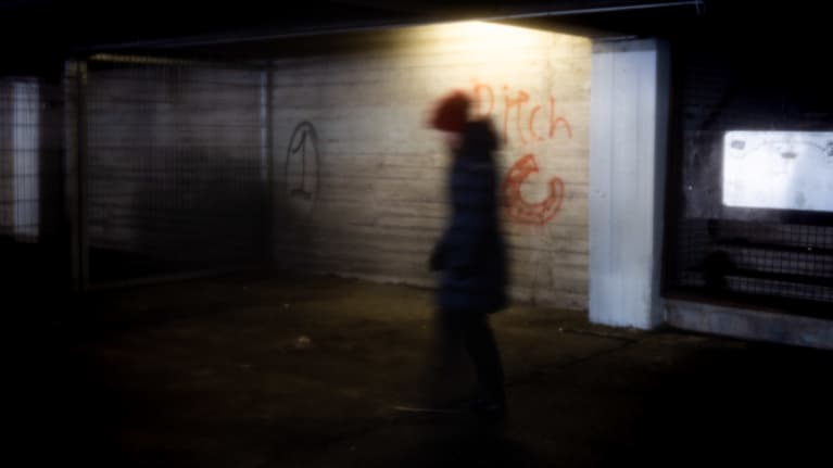 Nainen pimeähkössä autohallissa jonka seinässä lukee "Pitch".