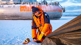 Fondation Tara Océanin johtaja Romain Troublé pystyttämässä telttaa meren jäälle Vaasan edustalla. Taustalla säätiön uusi tutkimusalus Tara Polar Station.