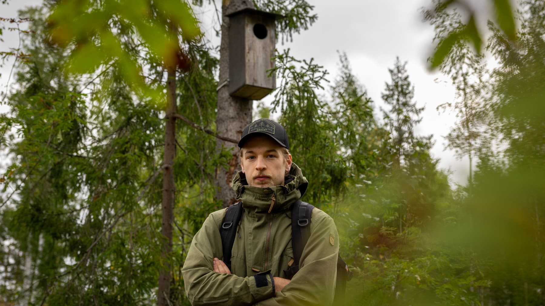 Luontokuvaaja Onni Rantanen. Taustalla lehtopöllön pönttö katkaistussa puussa.