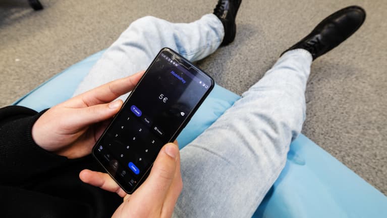 Henkilö käyttää MobilePay-sovellusta älypuhelimella.