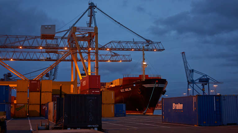 Fraktfartyg vid hamn med containrar.