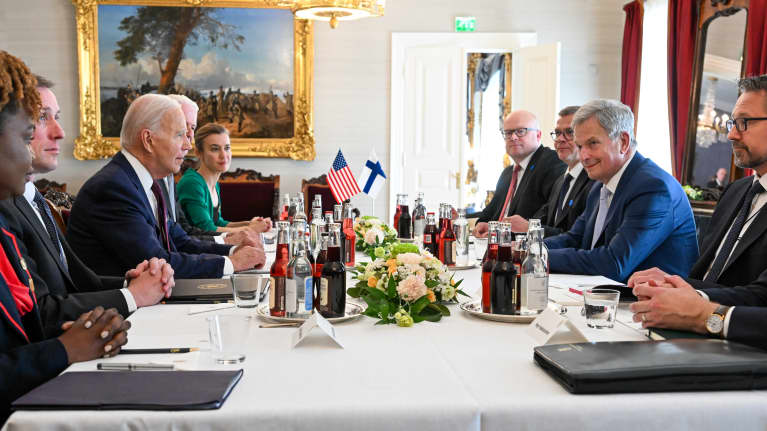 Presidentti Joe Biden ja presidentti Sauli Niinistö sekä muita ihmisiä kokous pöydän äärellä.