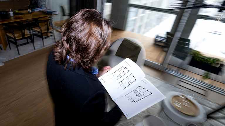 A person is looking at a brochure with floor plans of apartments.