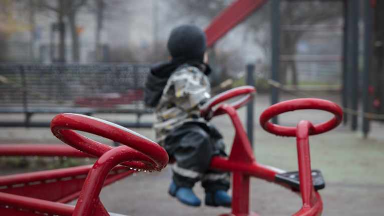 Litet barn sitter ensam i en karusell i en lekpark.