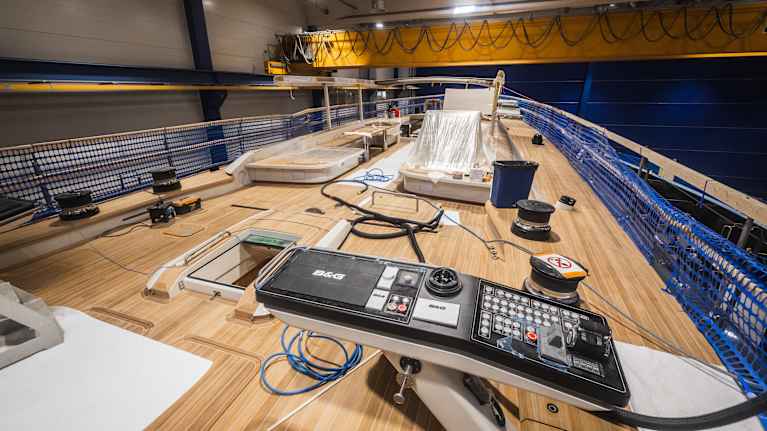 En stor segelbåt med trädurk syns inomhus, med kontrollpanel och utrustning placerade på däck.