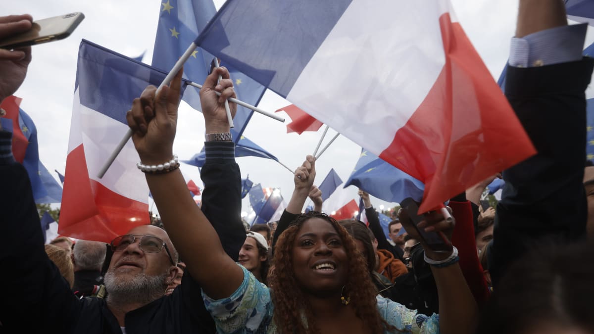 Glada människor som viftar med franska flaggor.
