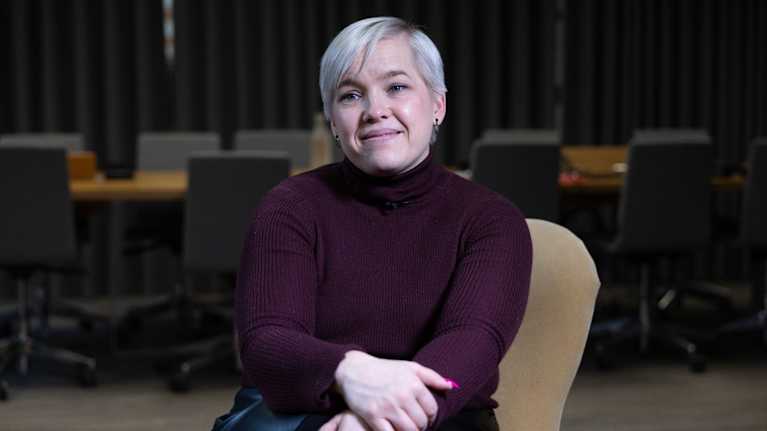 A blonde woman sits in a chair.
