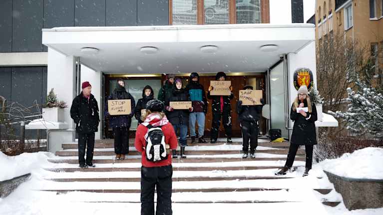 Mielenosoittajat pitelevät kylttejä Norjan suurlähetystön sisäänkäynnin edustalla.