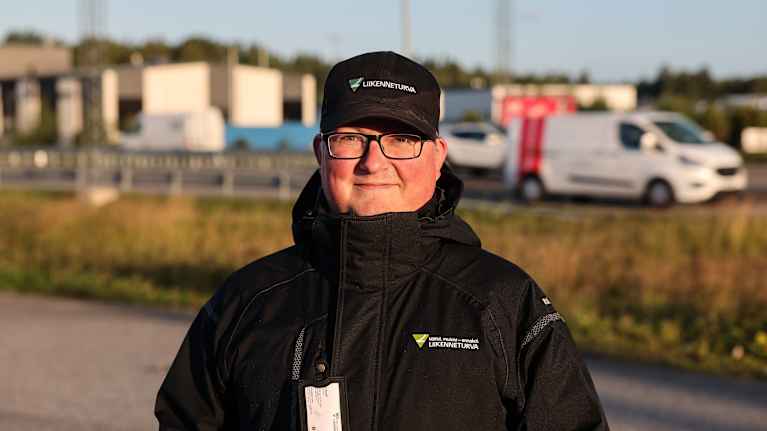 Mies seisoo vilkkaan autotien varressa. 