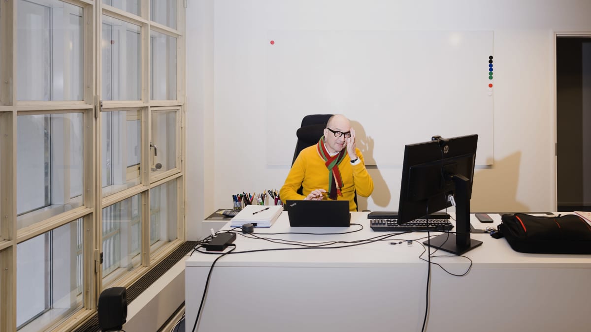  Thomas de Mallet Burgess istuu työhuoneessaan tietokoneen takana, kohentaa silmälasejaan. laaja kuva.