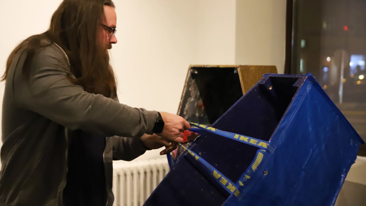Taiteilija Ilmari Wärri kantaa Ikea-kasseilla päällystettyä arkkua.