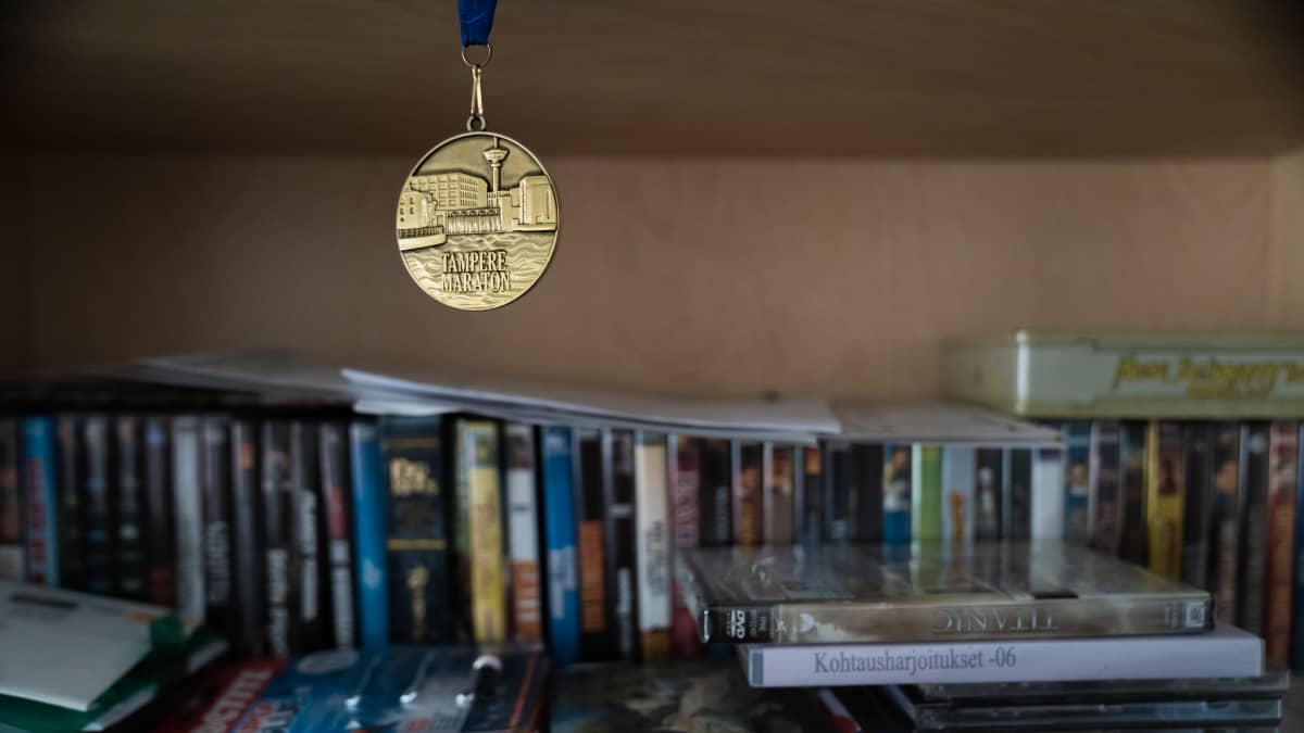 Petri Poikolaisen Tampereen maratonista voitettu mitali roikkuu kirjahyllyssä.