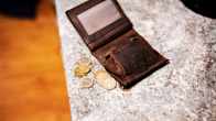 A wallet and a few coins on a table. 