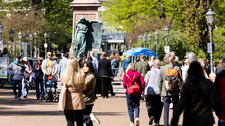 The photo shows people walking along the Helsinki Waterfront Promenade.