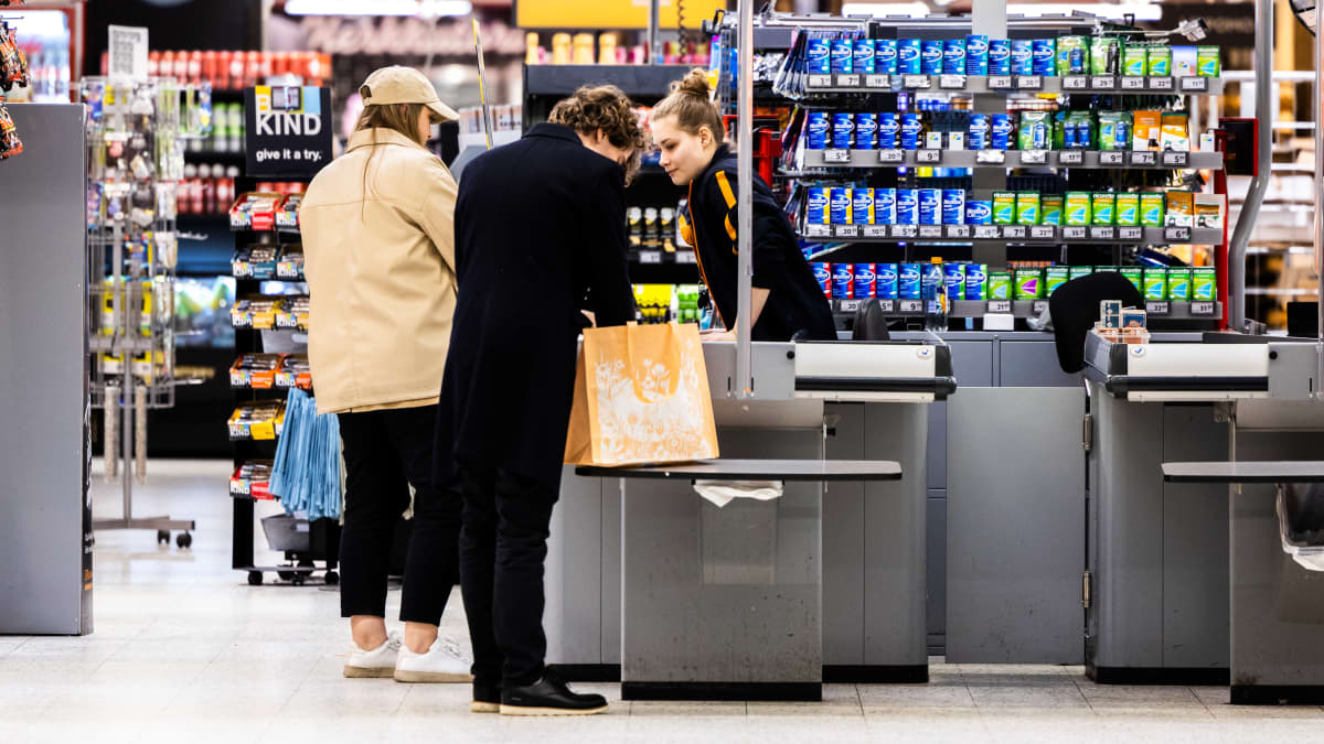 Ruokakaupan kassahenkilö asiakkaan kanssa.