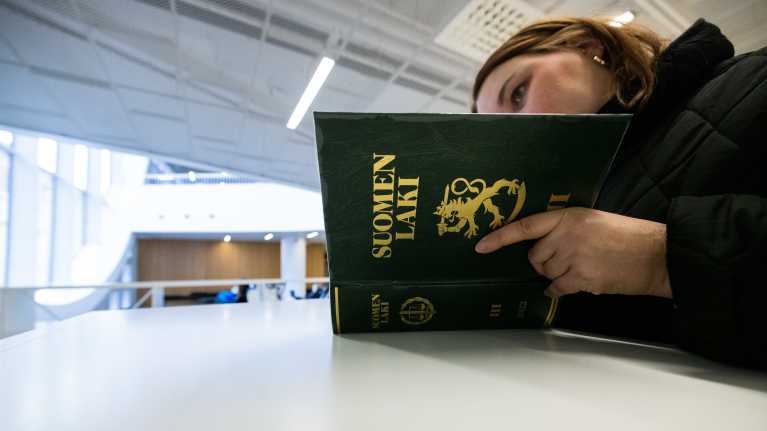 Henkilö lukee Suomen laki kirjaa.