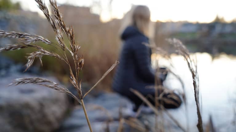 Nainen istuu rannalla.