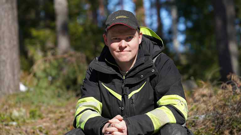 Thomas Lindholm tittar mot kameran, skog i bakrgunden.