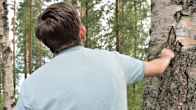 Andrei stands with his back to the camera, looking into the forest.