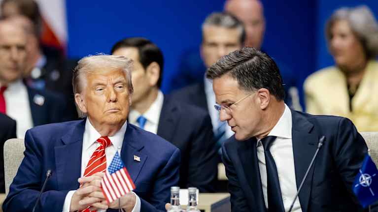 Trump ja Rutte pöydän ääressä, pienet USAN ja Naton liput pöydällä. 