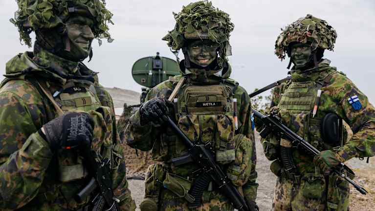 Three soldiers in Finnish Defence Forces uniforms and equipment during an exercise.