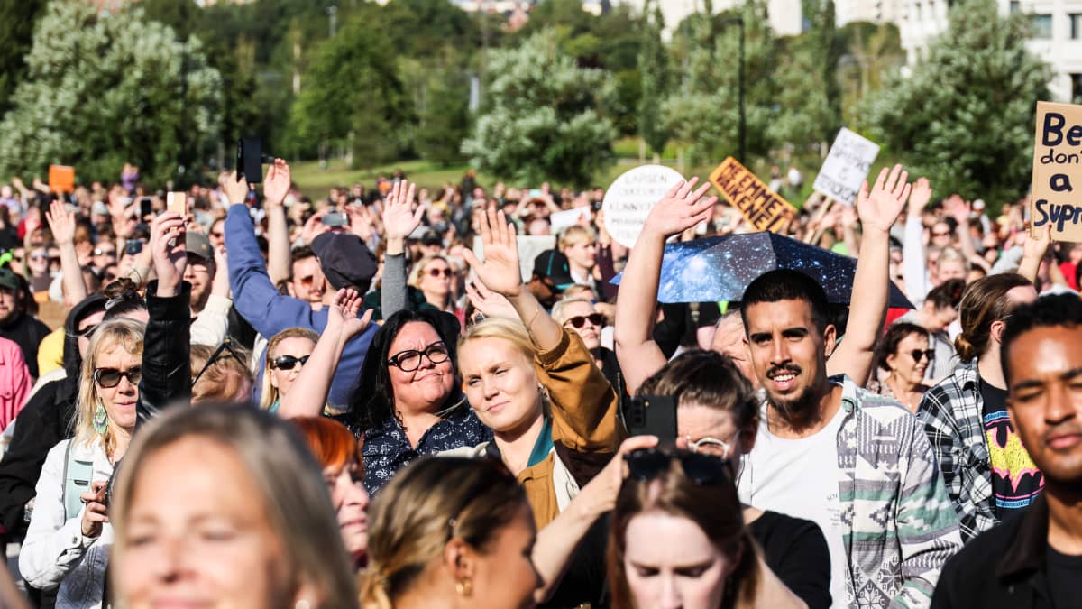 Mielenosoittajat kuuntelemassa esiintyjiä Töölönlahden tapahtumapuistossa.