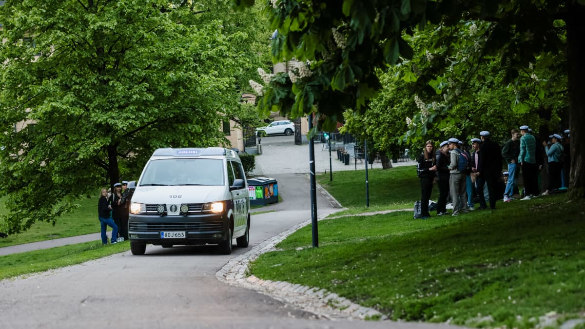 Poliisiauto ajaa puistossa jossa ylioppilaat juhlivat.