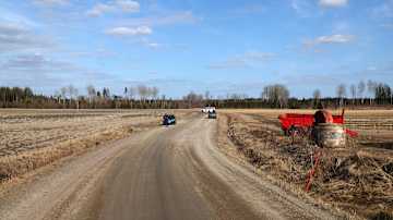 Poliisiauto poikittain maantiellä maalaismaisemassa.