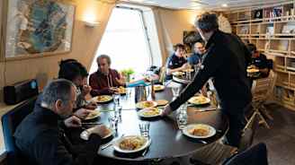 Ihmiset aterioivat pöydän ympärillä aluksella.