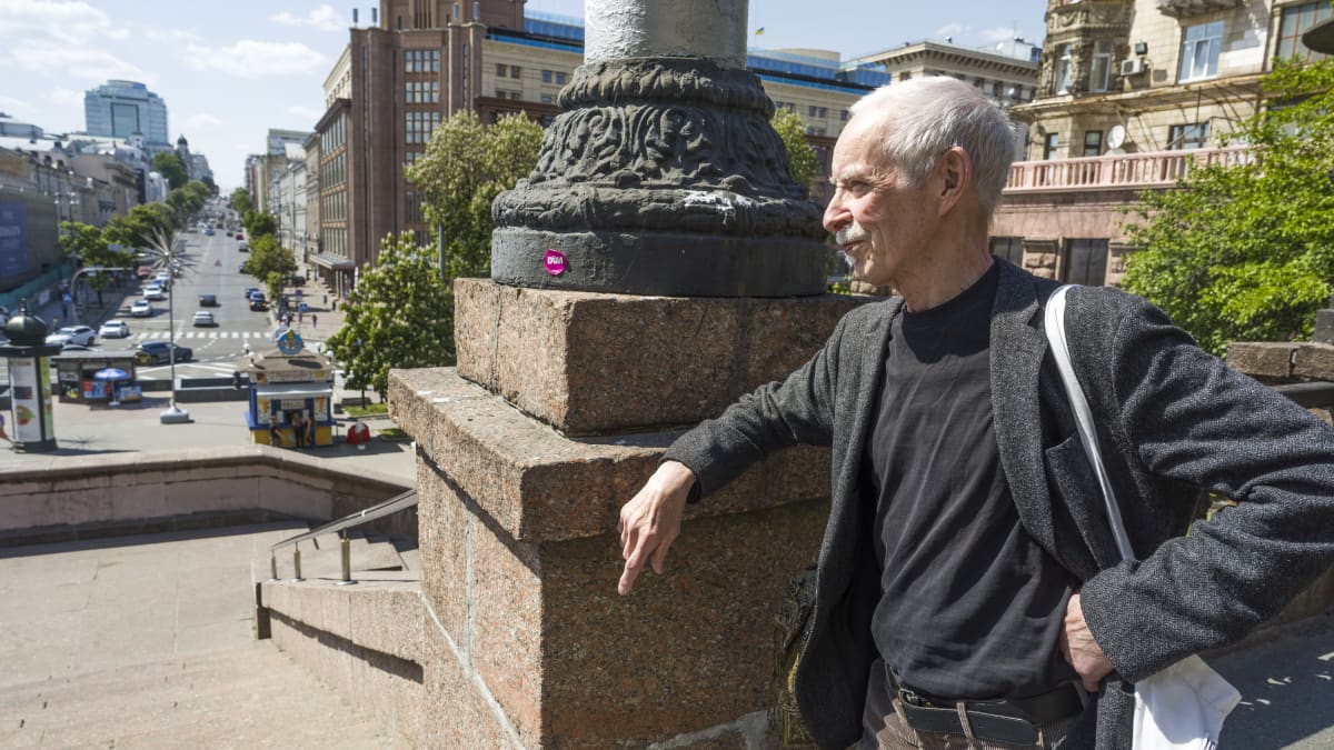 Sarjakuvapiirtäjä Heikki Paakkanen Kiovassa, nojaa muuriin ja katselee liikennettä kadulla.