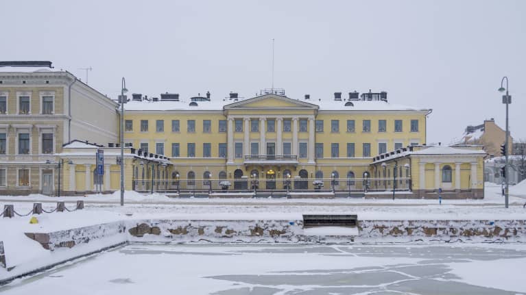 Tasavallan presidentin linna lumisateisessa, talvisen harmaassa kelissä, etualalla ns. kolera-allas.