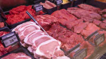 Beef and pork in a grocery store butcher department refrigerated display case.