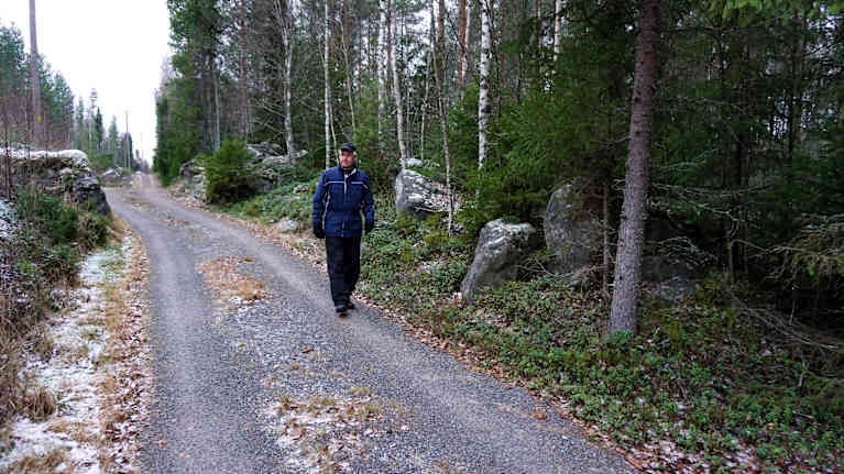 Man går på en skogsväg.