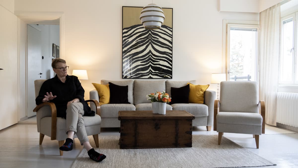 Marja Bastman istumassa olohuoneessaan Alvar Aallon suunnittelemassa kerrostalossa. 