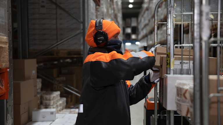 Logistiikkatyöntekijä kerää tavaraa rullakkoon. 