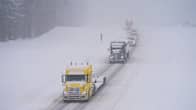 Lorries driving on a snow-covered highway in winter weather.