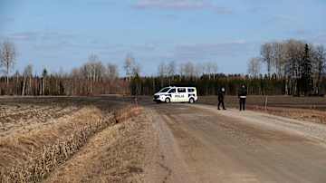 Finnish police van blocking a country road, with a field, trees and blue sky seen in the background.