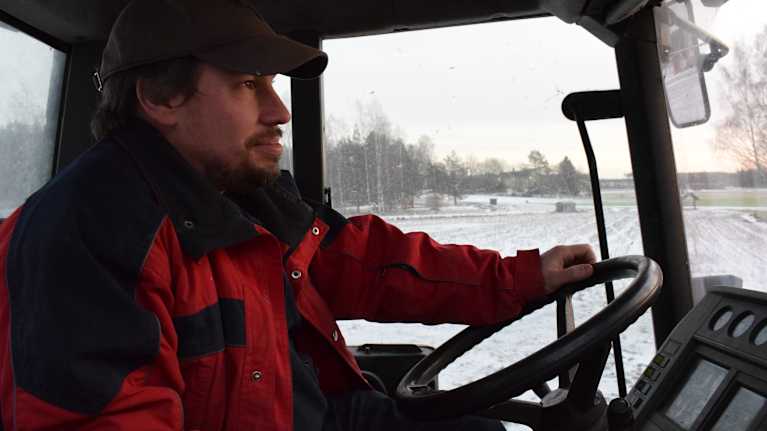 Anders Abrahamsson sitter i traktorhytten, vinterlandskap utanför.