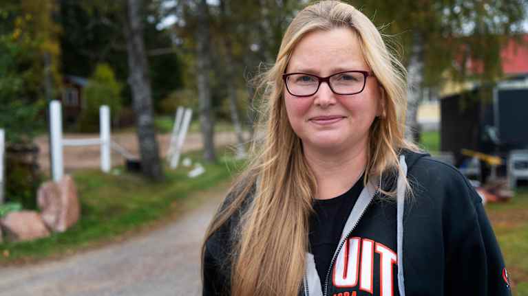 Ljushårig kvinna med svarta glasögon tittar in mot kameran. 