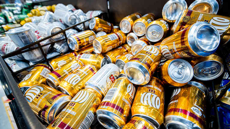 Golden beer cans are stacked in storage bins.