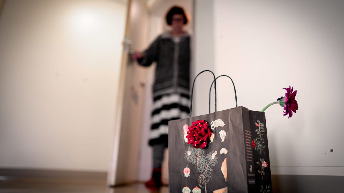 Koronakaranteenissa oleva vanhus katsoo ovelta hänelle rappuun jätettyä lahjakassia.