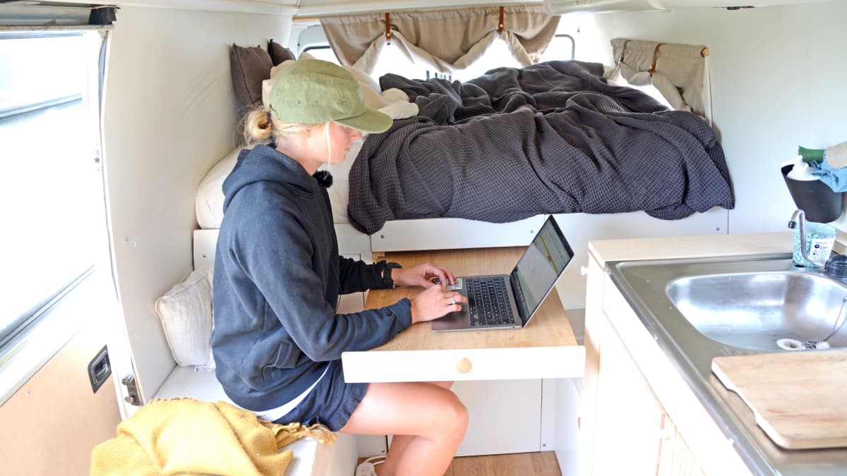 Nainen kirjoittaa tietokoneella pakettiauton sisällä