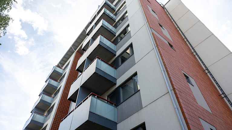 A modern apartment building with several balconies and red brick walls.